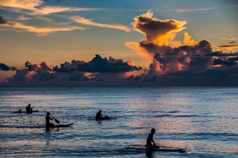 Surfers at sunset in Guam
