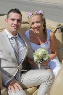Bride and groom posing in the back seat of an open car