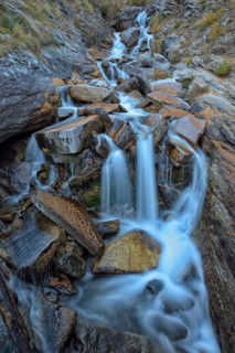 Mountain stream with fallen larch needles on the stones