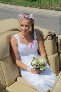 Bride posing in the back seat of an open car