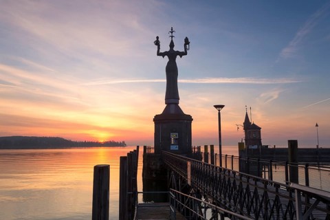 Statue of Imperia at the entrance of the harbour of Konstanz at sunrise