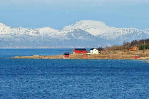 Headland with houses in the blue water of Hadselfjord and Raftsund