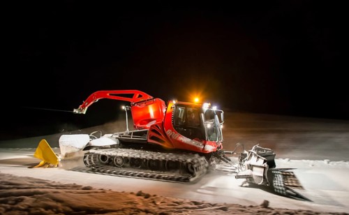 Snowcat planing ski slope with rope at night