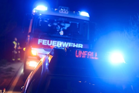 Fire engine and police car with flashing blue lights and the LED display 'Unfall'