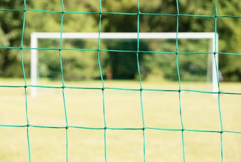 Empty soccer field seen through the net of the goal