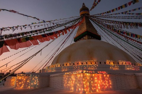 Boudhanath Stupa decorated with prayer flags and lights for the full moon festival