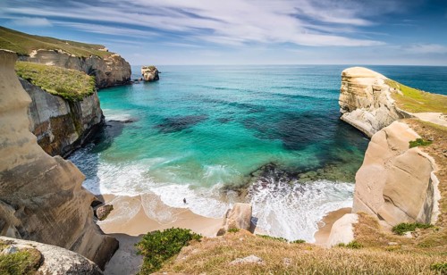 Solitary person on the rocky cliffs of the Pacific coast in the distance