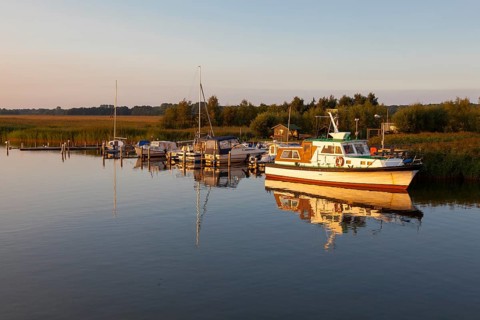 A small motorboat anchored at a landing stage on the Bodden lagoon