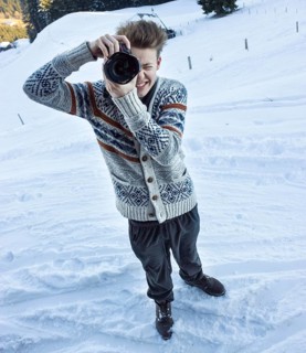 Young man in the snow taking a picture with a digital SLR camera