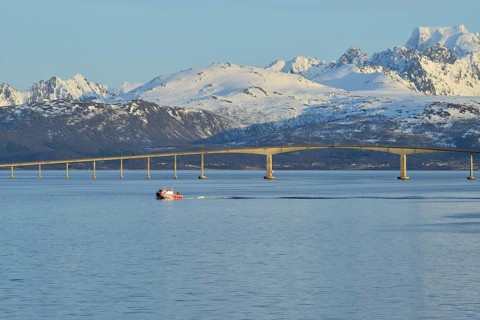 Red boat in front of Hadsel Bridge across the strait