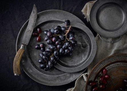 Pewter plates with grapes on a black underground