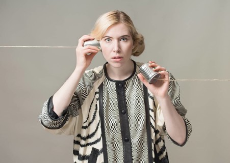 Blond woman listening with tin can phone