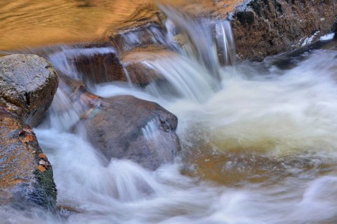 Water running over rocks in a brook in autumn