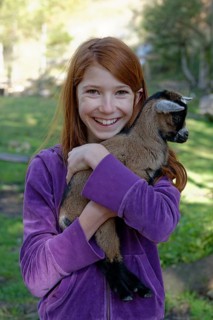 Girl holding a dwarf goat in the petting zoo at Schopperalm