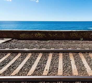 Railroad tracks in front wall with graffiti in front of the sea