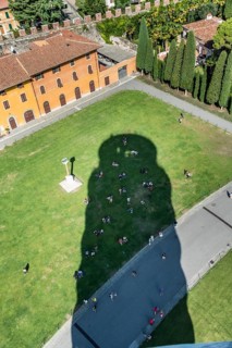 Tourists cooling off in the shade of the Leaning Tower of Pisa