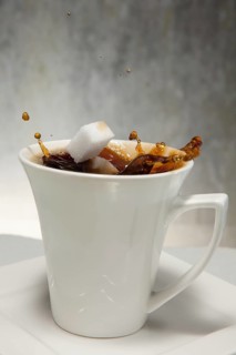 Two sugar cubes falling into a cup of coffee
