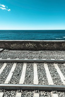 Railroad tracks in front wall with graffiti in front of the sea