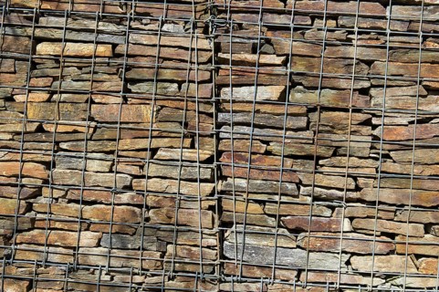 Wall with stacked stones behind steel mesh