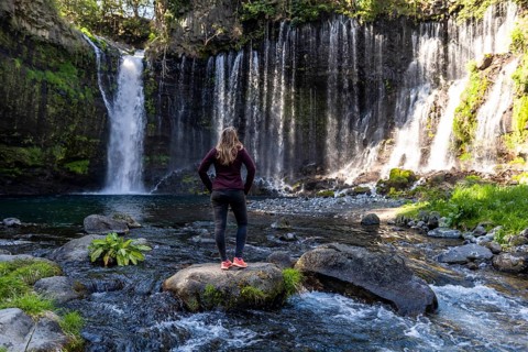 Young woman standing on a stone in a river