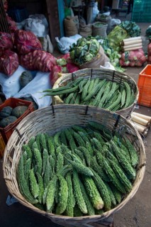 Bitter melons and cucumbers in woven baskets on the market