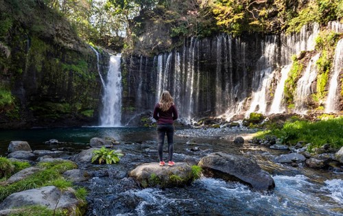 Young woman standing on a stone in a river
