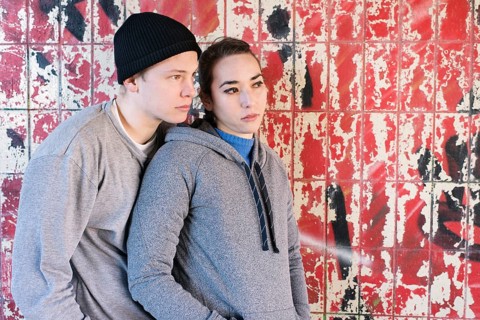 Casual and relaxed young man and woman waiting in front of grafitti wall in urban area