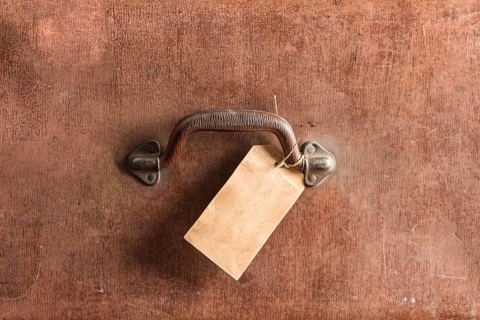 Handle and luggage tag of an old brown leather bag