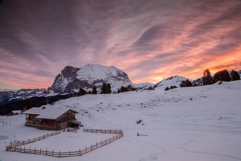 Sunrise over Mt Plattkofel and a mountain hut in winter