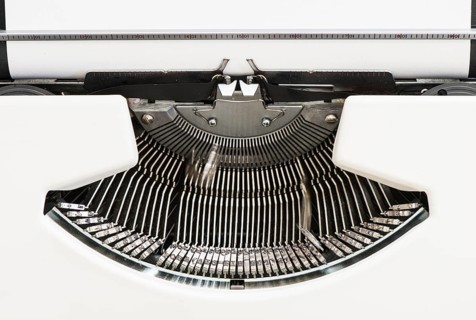 Detail view of an old fashioned typewriter from the 1970s with blank paper and moving hammer heads