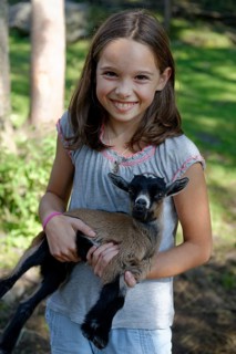Girl holding a dwarf goat in the petting zoo at Schopperalm