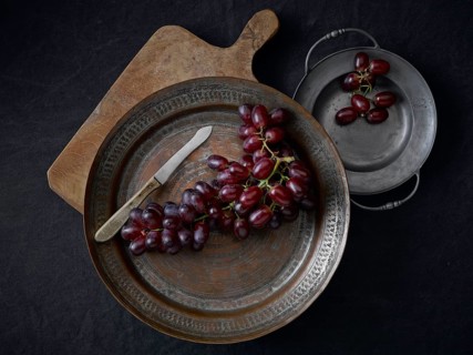 Pewter plates with grapes on a black underground