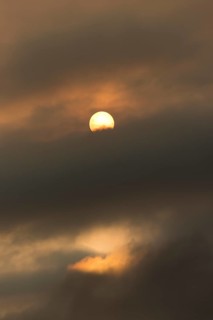 Sun behind clouds and brownish ash and gas clouds of the Holuhraun fissure eruption