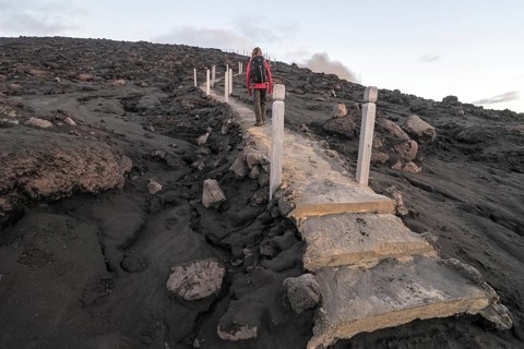 Woman climbing stairs to the crater of Mount Yasur volcano