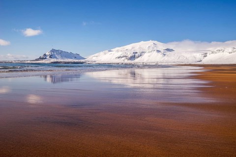 Sunny winter day on the sandy beach in front of Snaefellsjokull volcano