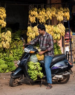 Man on scooter by a banana stand