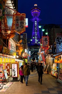 Many colorful neon signs in a pedestrian zone with shops and restaurants