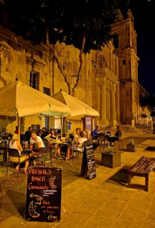 Tourists sitting in an outdoor restaurant at St. John's Co-Cathedral