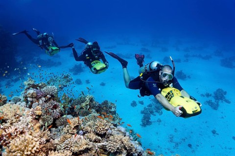 Divers with diver propulsion vehicles exploring a coral reef