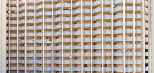Facade of a skyscraper with satellite dishes on balconies