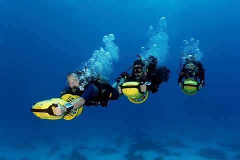Divers with diver propulsion vehicles exploring a coral reef