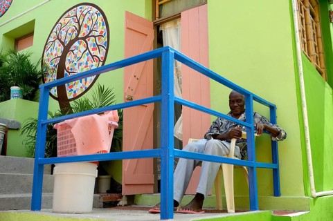 Old man sitting in front of a house he built with the support of a charity