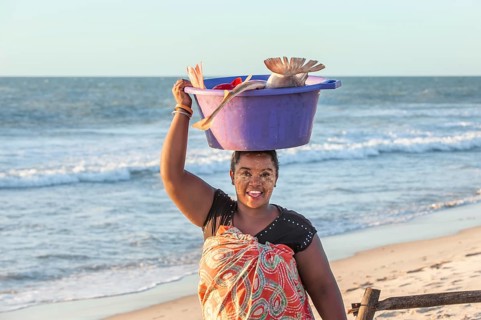 Malagasy woman carrying fish in a tub on her head