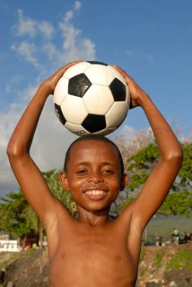 Smiling boy holding a football on his head