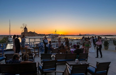People on the evening in front of the salt pans Ettore Infersa wind mill with salt museum