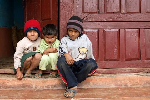 Nepalese children sitting in front of a doorway