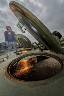 A man cutting up an armored vehicle type Marder with a torch