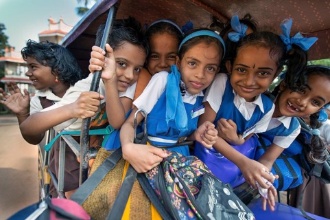 School children in school uniforms sitting in a rickshaw
