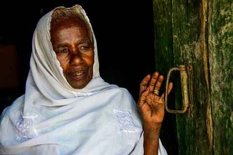 Friendly old woman standing in a door frame near Keren