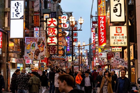Crowd crowded in pedestrian zone with lots of illuminated advertising for restaurants and shopping centers